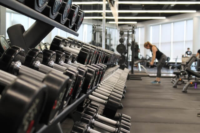 Spor salonu randevu uygulaması. Kadın spor salonunda ağırlık çalışıyor.